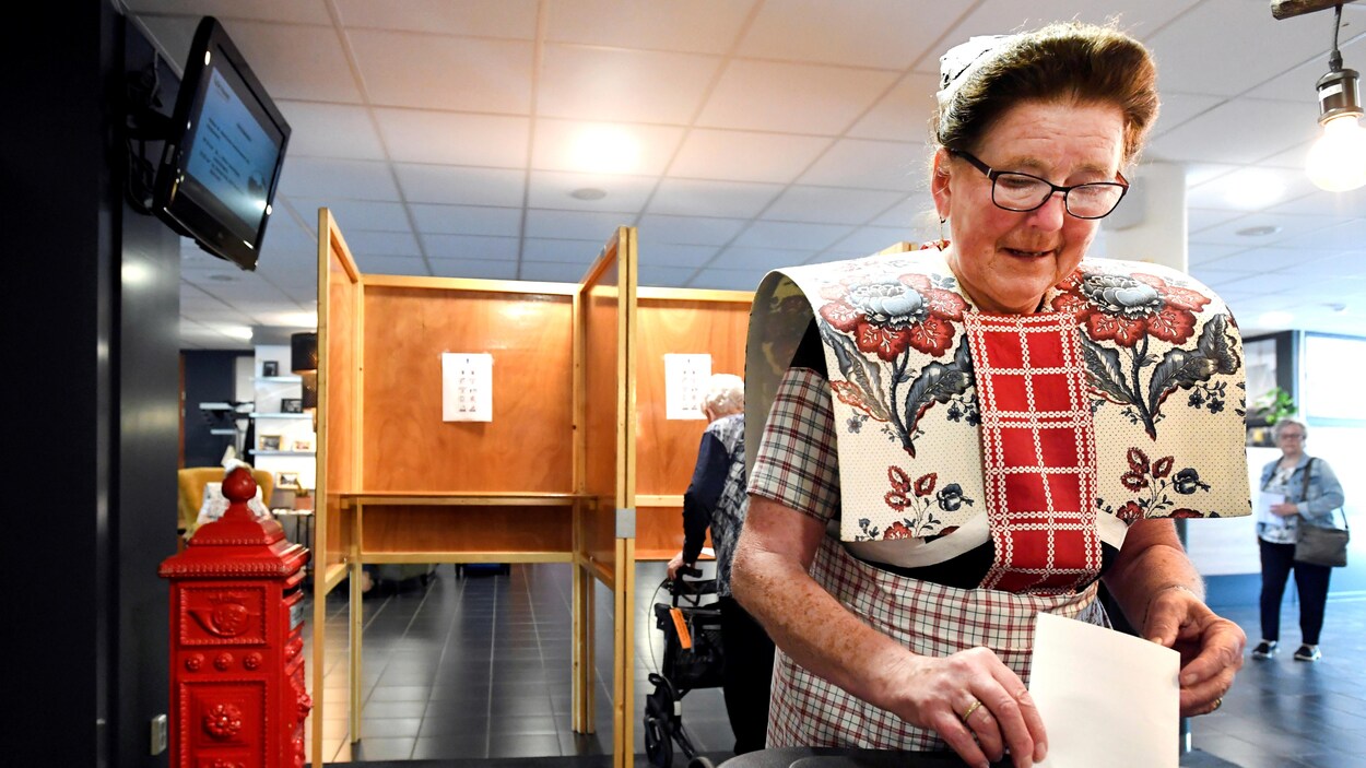 Une femme glisse un bulletin de vote dans une urne.