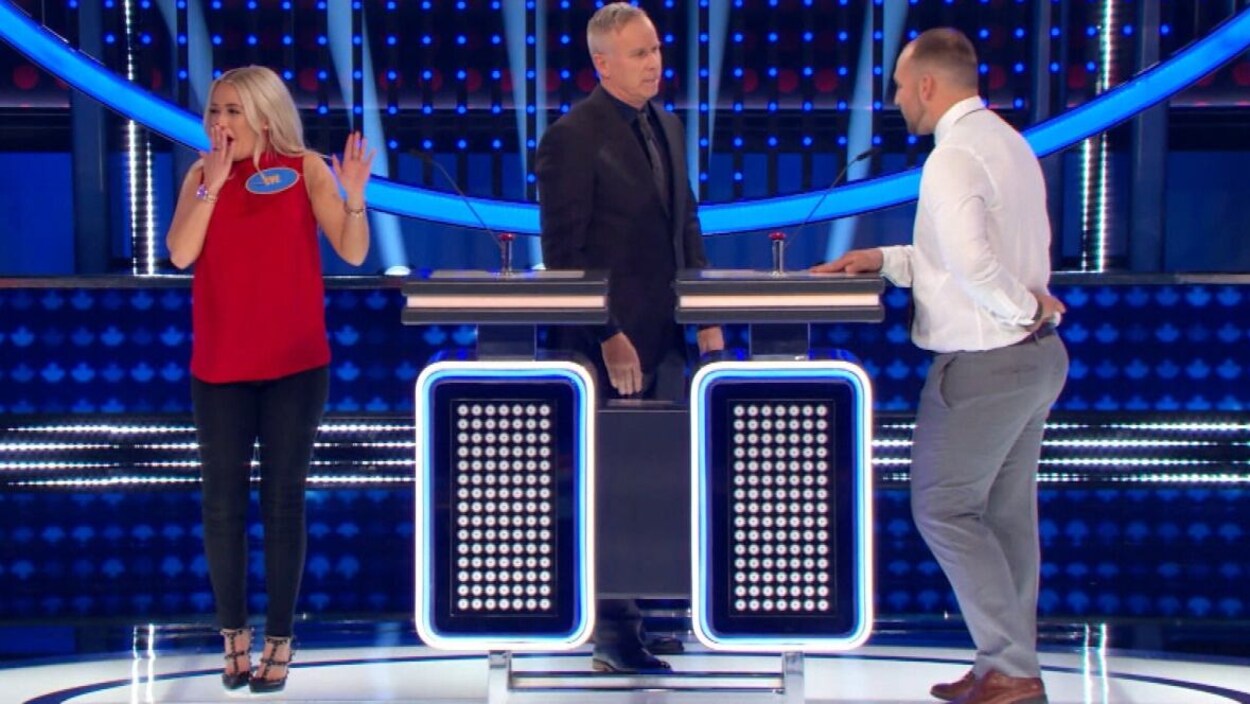 Eve Dubois, sur un plateau de télévision, a l'air surprise, la main devant la bouche.