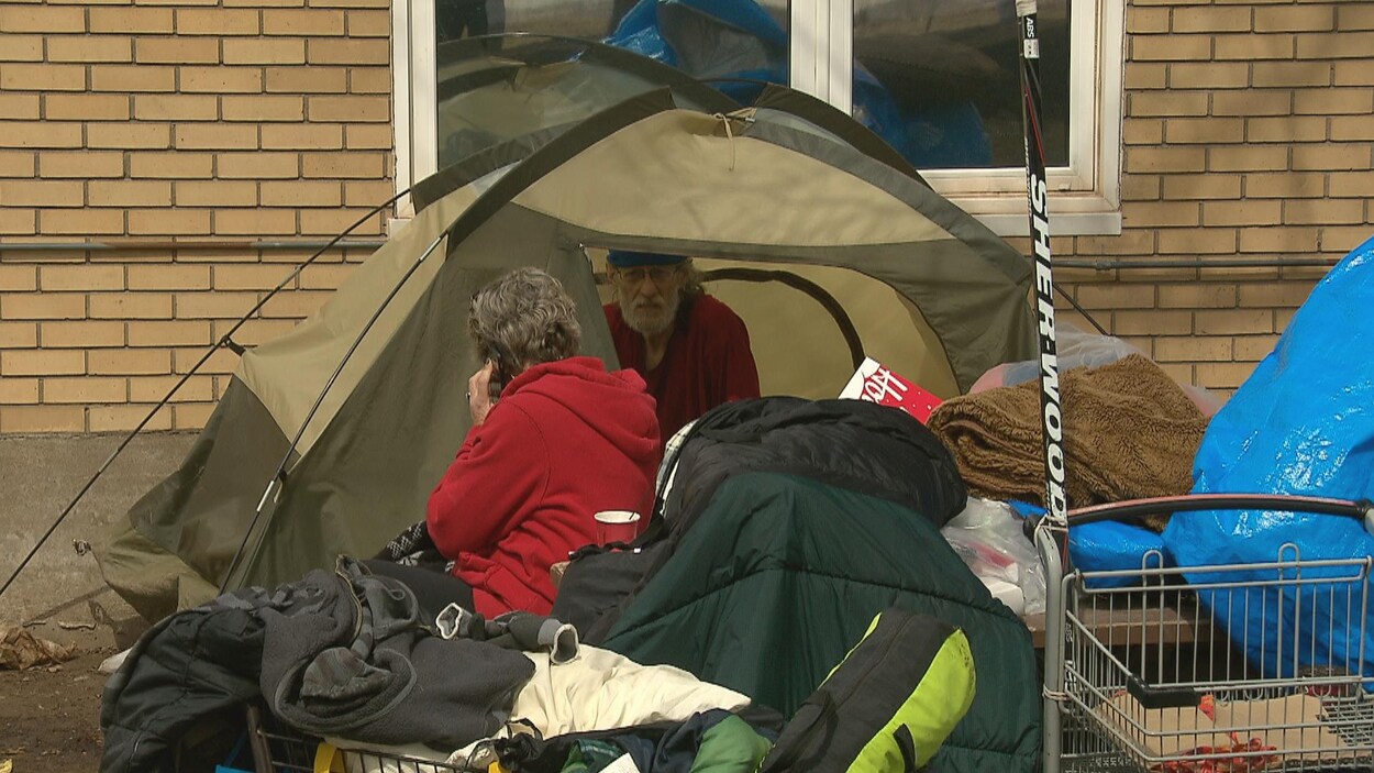 Un couple de sans-abri se prépare à ranger son campement.