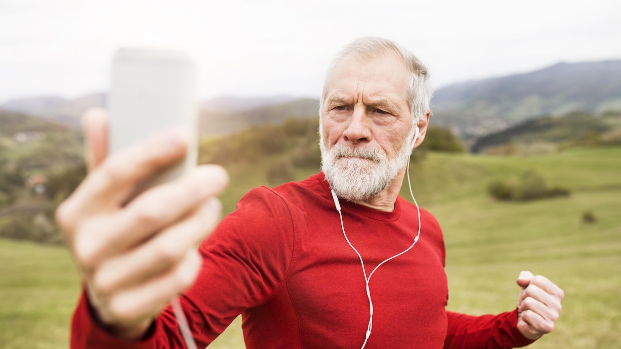 Un homme d'un certain âge prend un selfie en s'entraînant à l'extérieur.