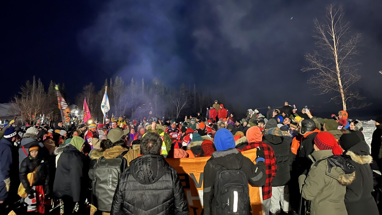 Une foule de plus d'une centaine de personnes regarde au loin.