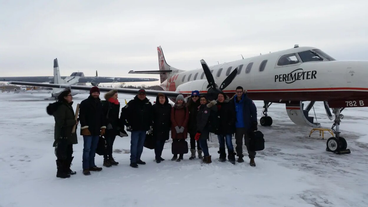 Dix professionnels de la santé avec des manteaux d'hiver devant un petit avion.