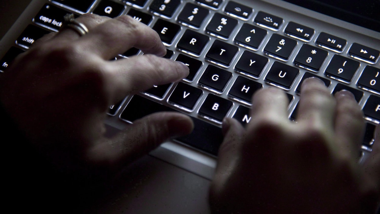 Des mains devant un clavier d'ordinateur.