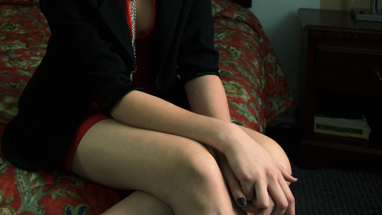 Femme assise sur un lit.