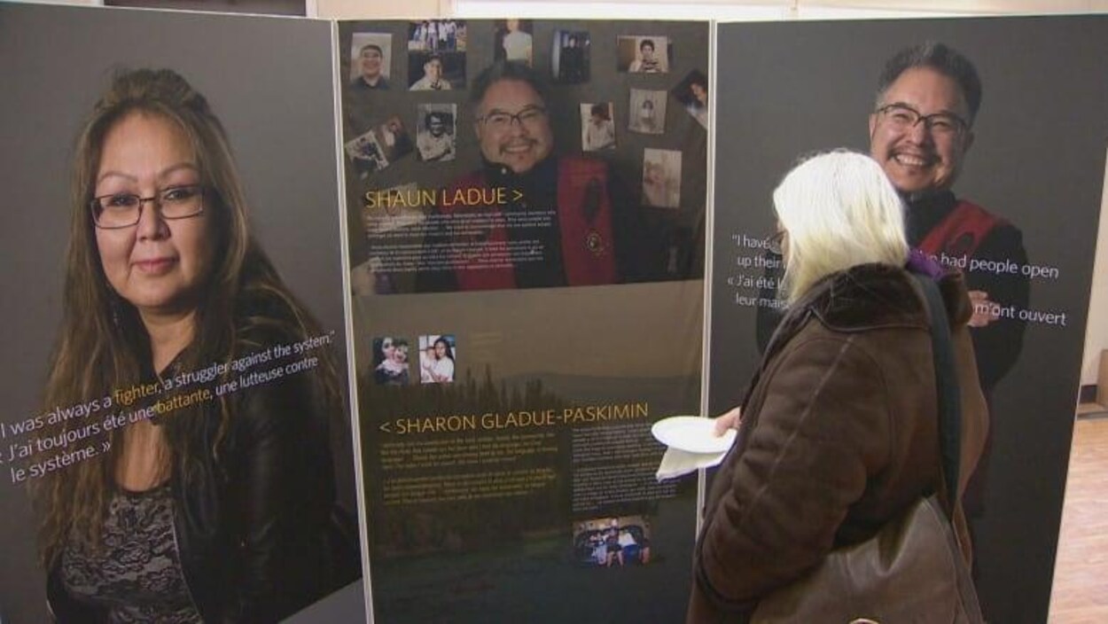 Une femme regarde les panneaux de l'exposition.