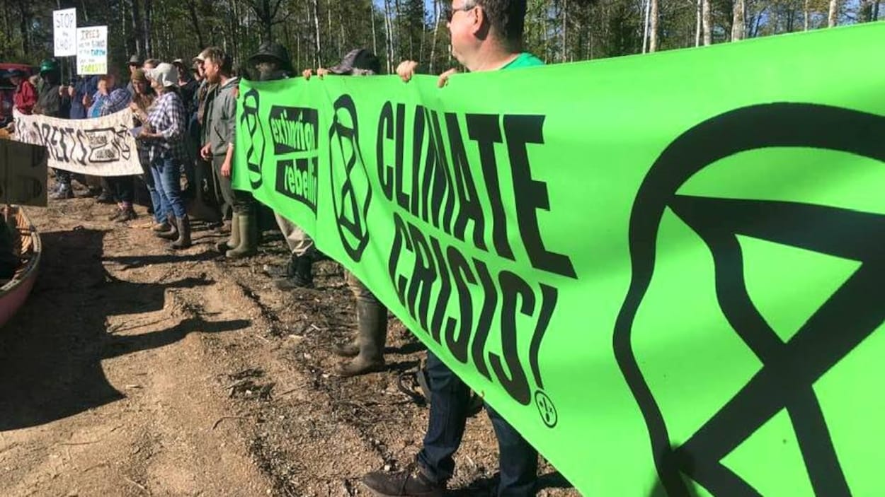 Des manifestants dressent une bannière verte d'Extinction Rebellion.