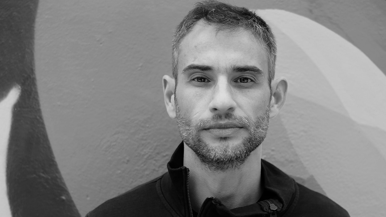 Portrait en noir et blanc de l'auteur Fabien Philippe, en extérieur, devant un mur peint.