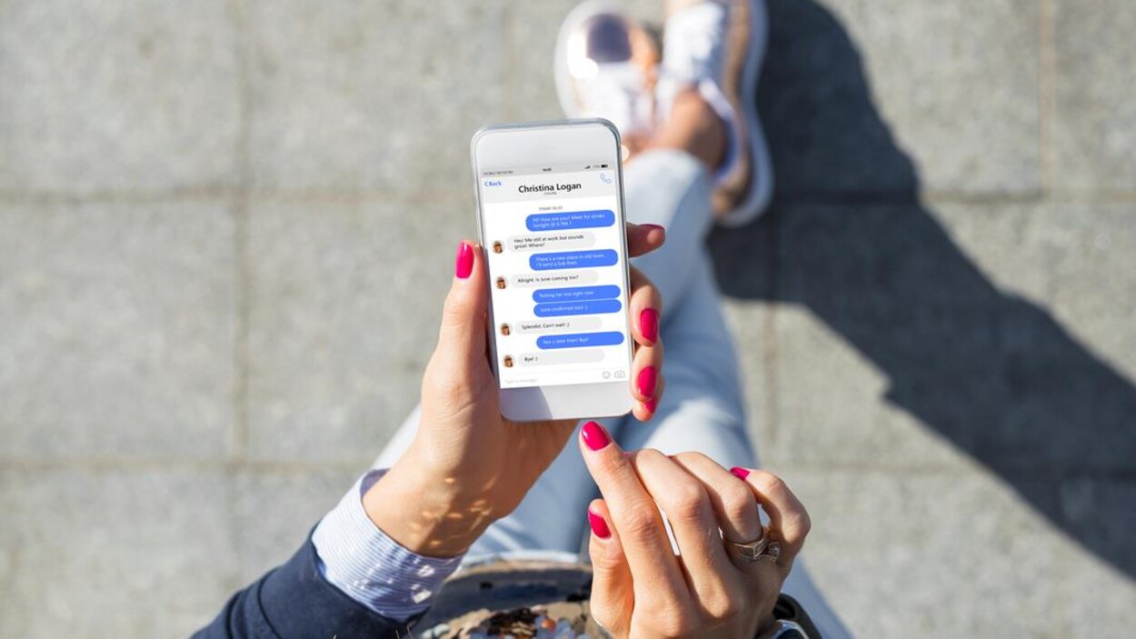 Vue en plongée de l'écran d'un téléphone intelligent qui montre une application de messagerie utilisée par une femme.