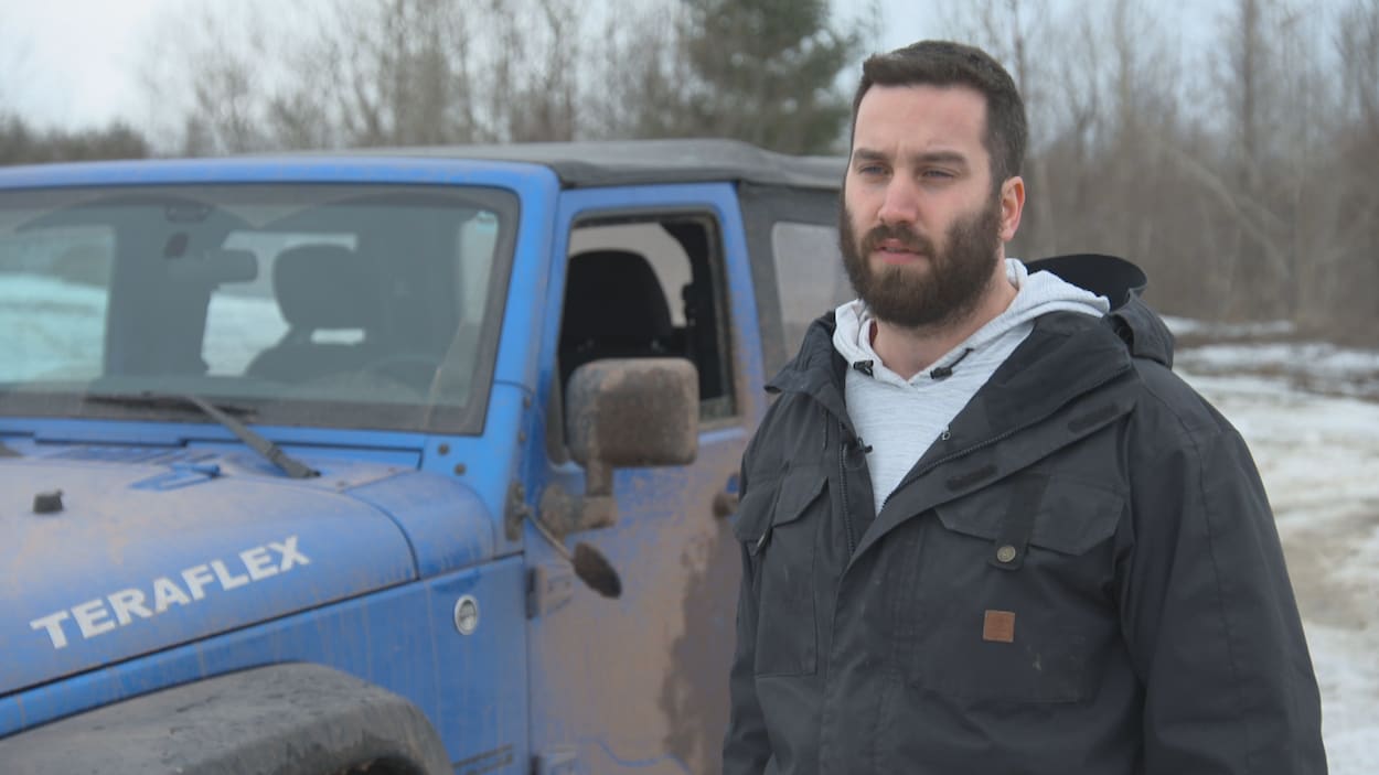 Shawn Leblanc, portant un manteau noir, discutant avec le journaliste lors d'une entrevue devant son véhicule Jeep bleu. Shawn Leblanc, portant un manteau noir, discutant avec le journaliste lors d'une entrevue devant son véhicule Jeep bleu.