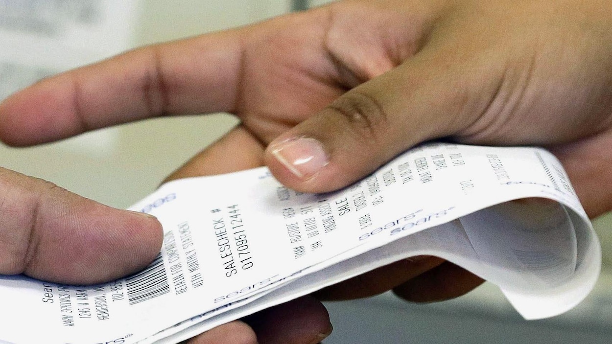 Deux mains s'échangent un ticket de caisse.