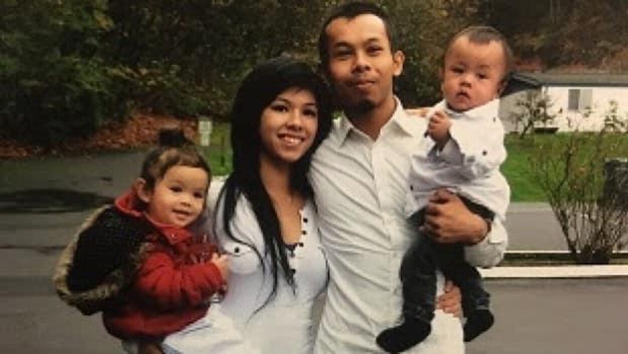 Chacun des parents porte un des enfants et pose pour la photo Chacun des parents porte un des enfants et pose pour la photo