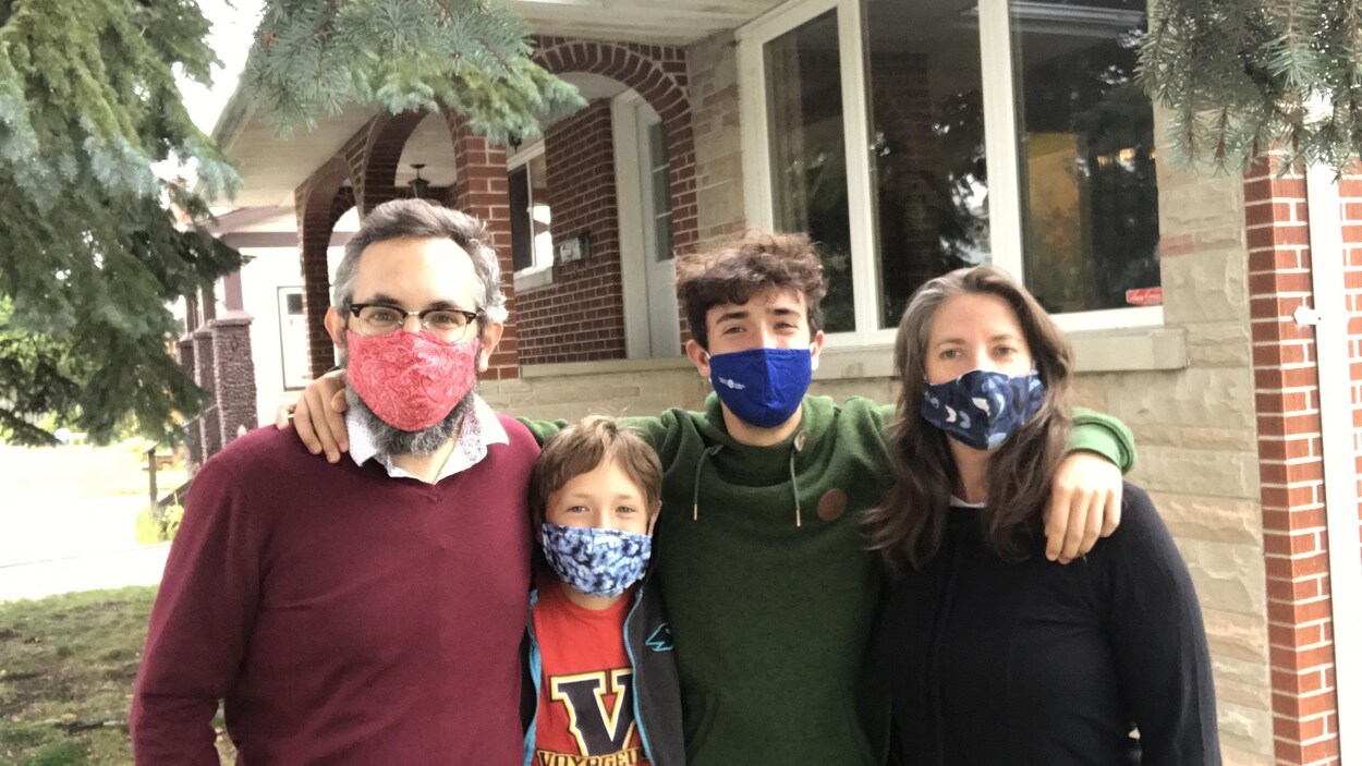 Quatre personnes sont près l'une des autres avec des masques.