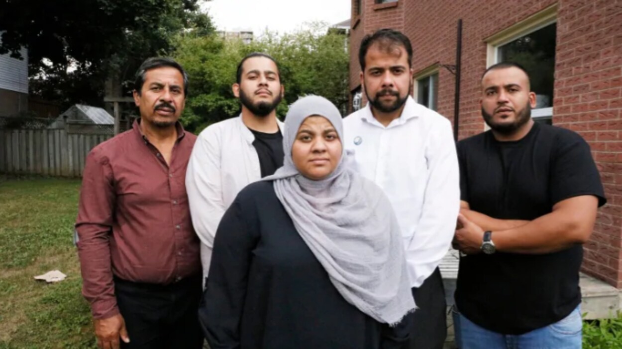 Une famille de cinq personnes : 4 hommes derrière et une femme voilée devant