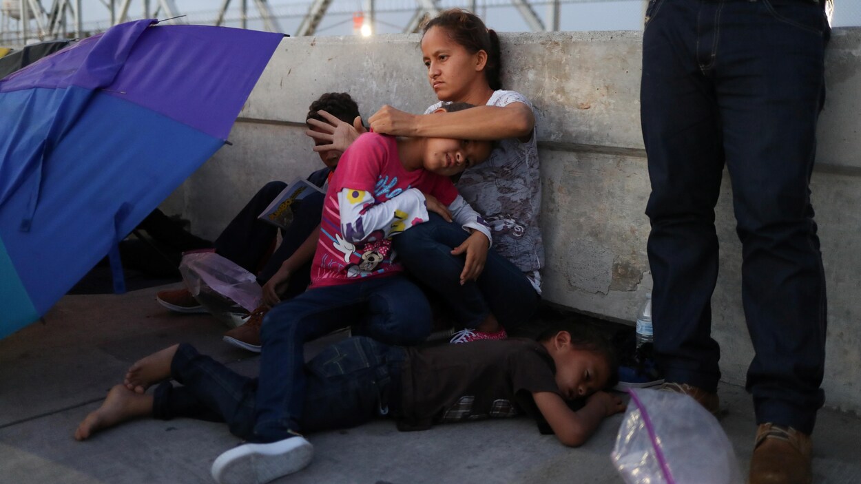 Une femme et des enfants sont assis par terre.