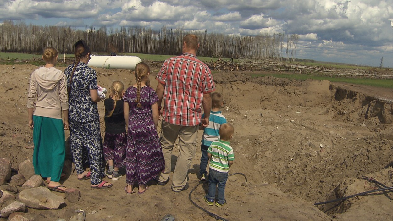 La famille Peters de dos fait face au trou laissé par la démolition de sa maison brûlée.