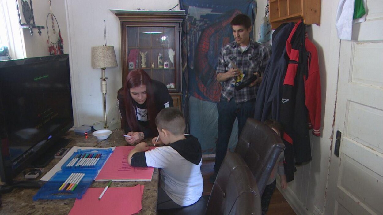 Hunter, 5 ans, fait dos à la caméra, il dessine assis à un bureau. Ses parents, Mélissa et Simon le regardent.