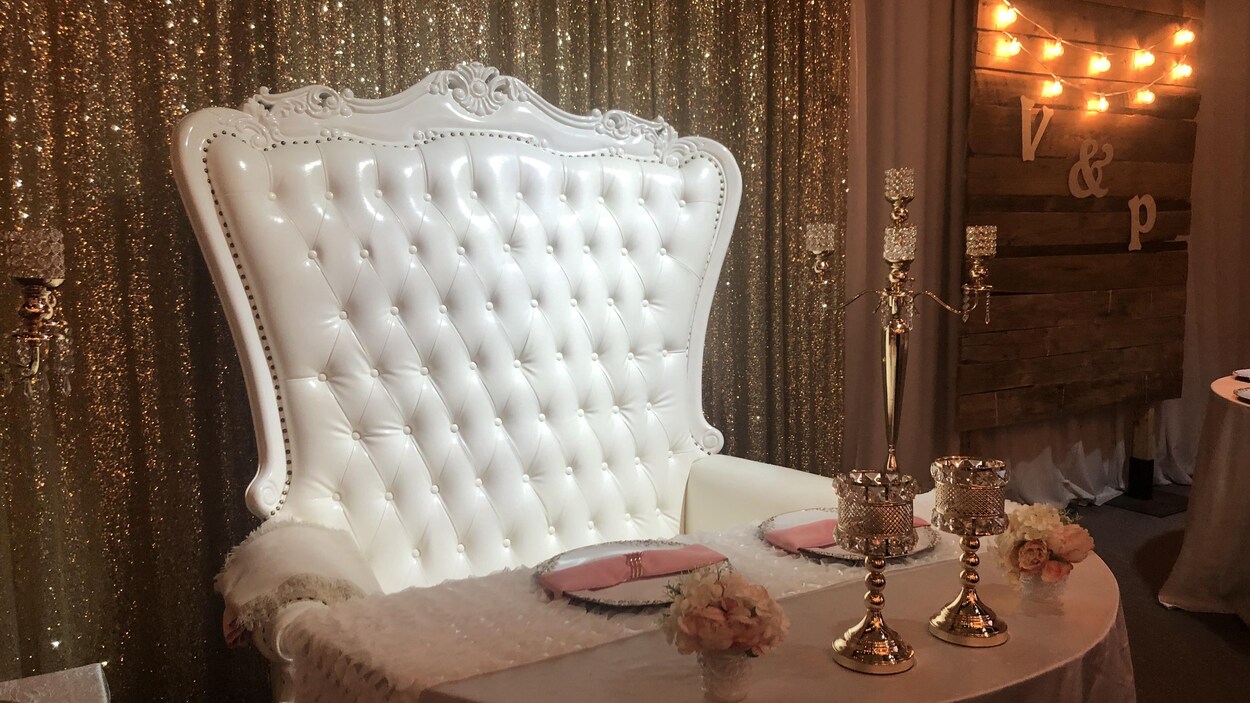 Une chaise capitonnée blanche dans un décor vide de réception de mariage.