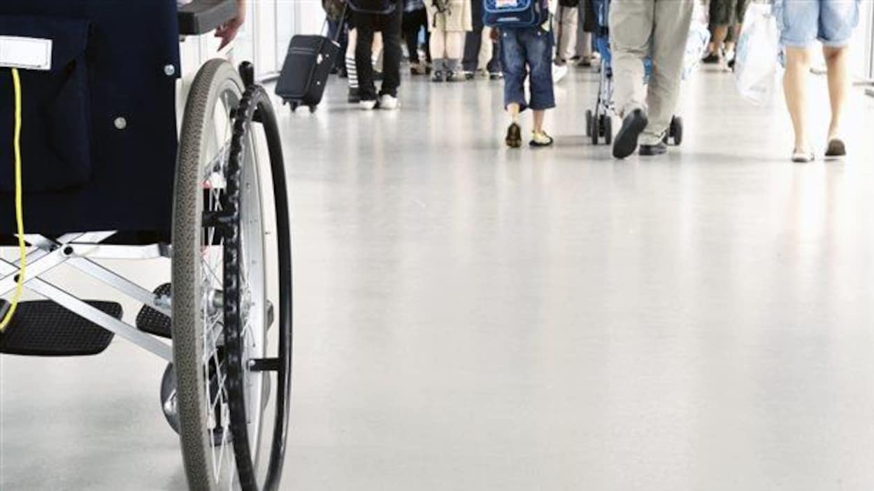 Une personne circule à fauteuil roulant parmi des gens qui n'en ont pas besoin pour se déplacer. Une personne circule à fauteuil roulant parmi des gens qui n'en ont pas besoin pour se déplacer.