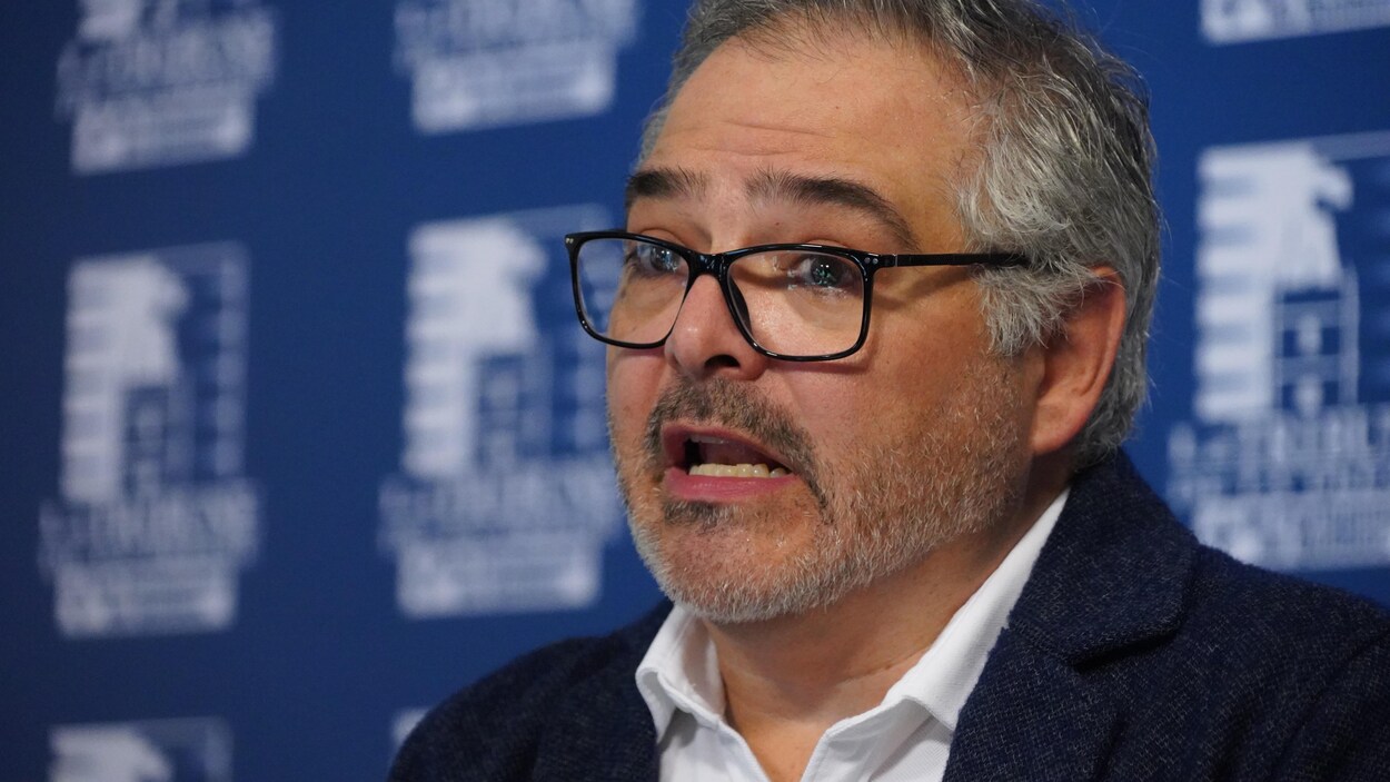 Un homme s'adresse aux médias en conférence de presse.