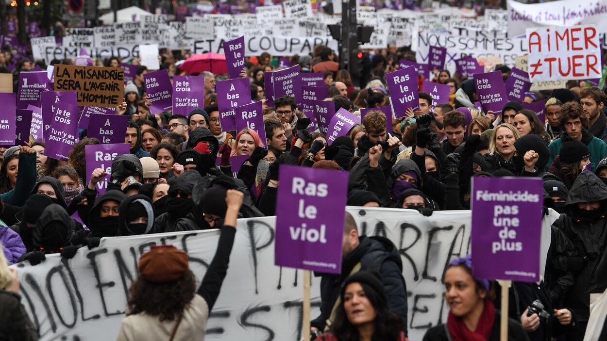 Des militantes portent des pancartes violettes où il est écrit « Ras le viol ».