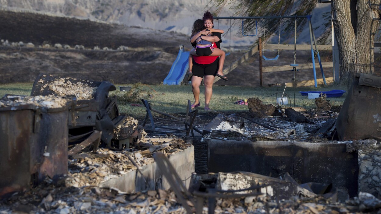 Une mère et sa fille devant les ruines de leur maison de la Première Nation d'Ashcroft, en Colombie-Britannique. Les feux de forêt ont fait rage dans l'intérieur de la province en 2017.