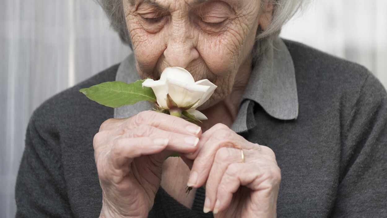 Une femme sent une rose.