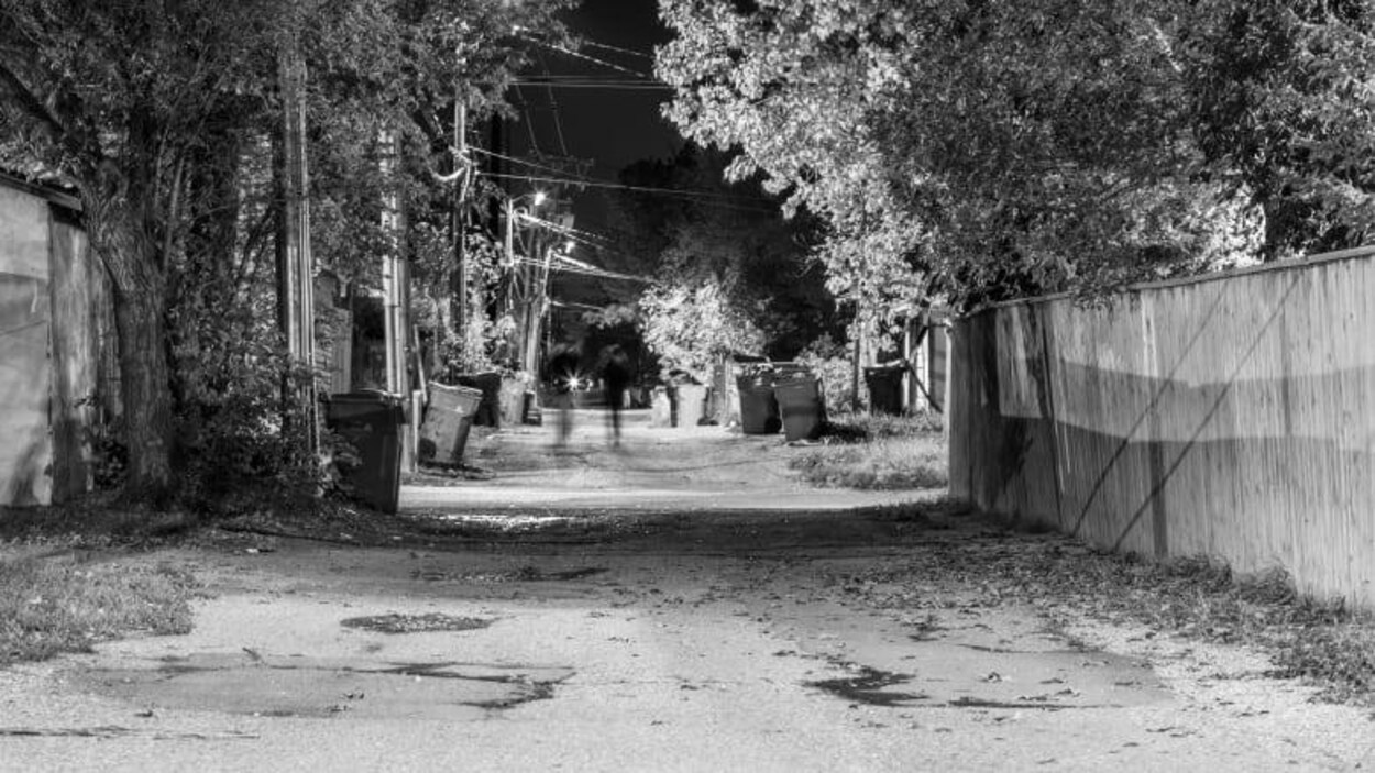 Une silhouette de femme dans une ruelle la nuit.