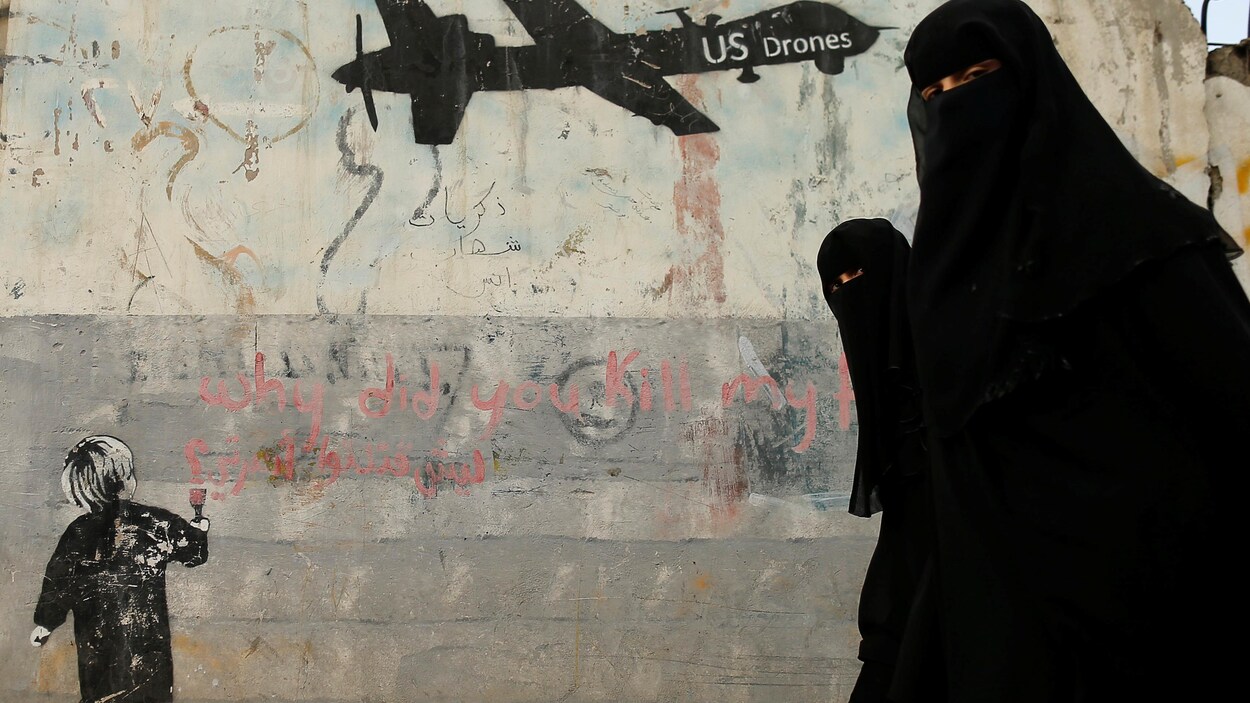 Des femmes passent devant une murale dénonçant les frappes aériennes de la coalition internationale à Sanaa, au Yémen. Des femmes passent devant une murale dénonçant les frappes aériennes de la coalition internationale à Sanaa, au Yémen.