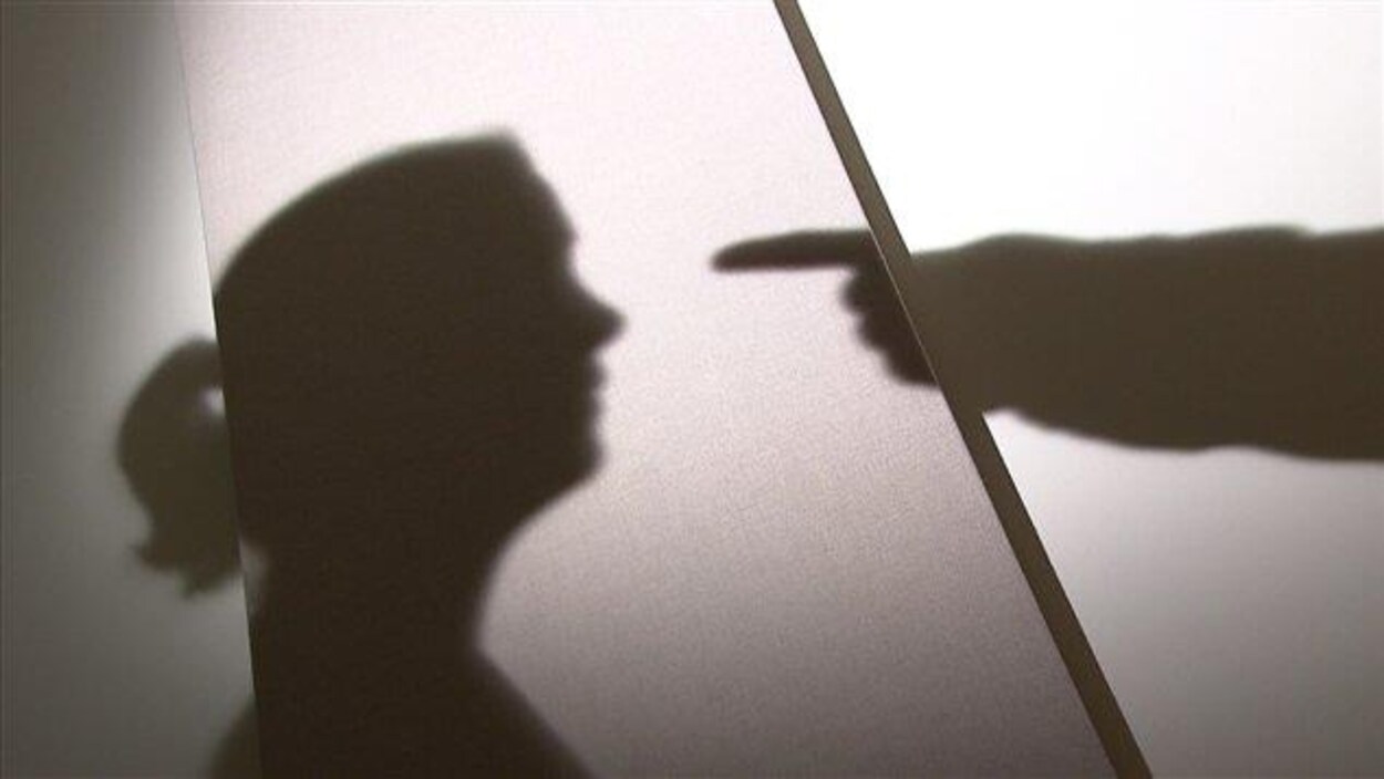 Ombres sur un mur : une femme de profil avec une queue de cheval, un bras tendu vers elle, le doigt pointé.