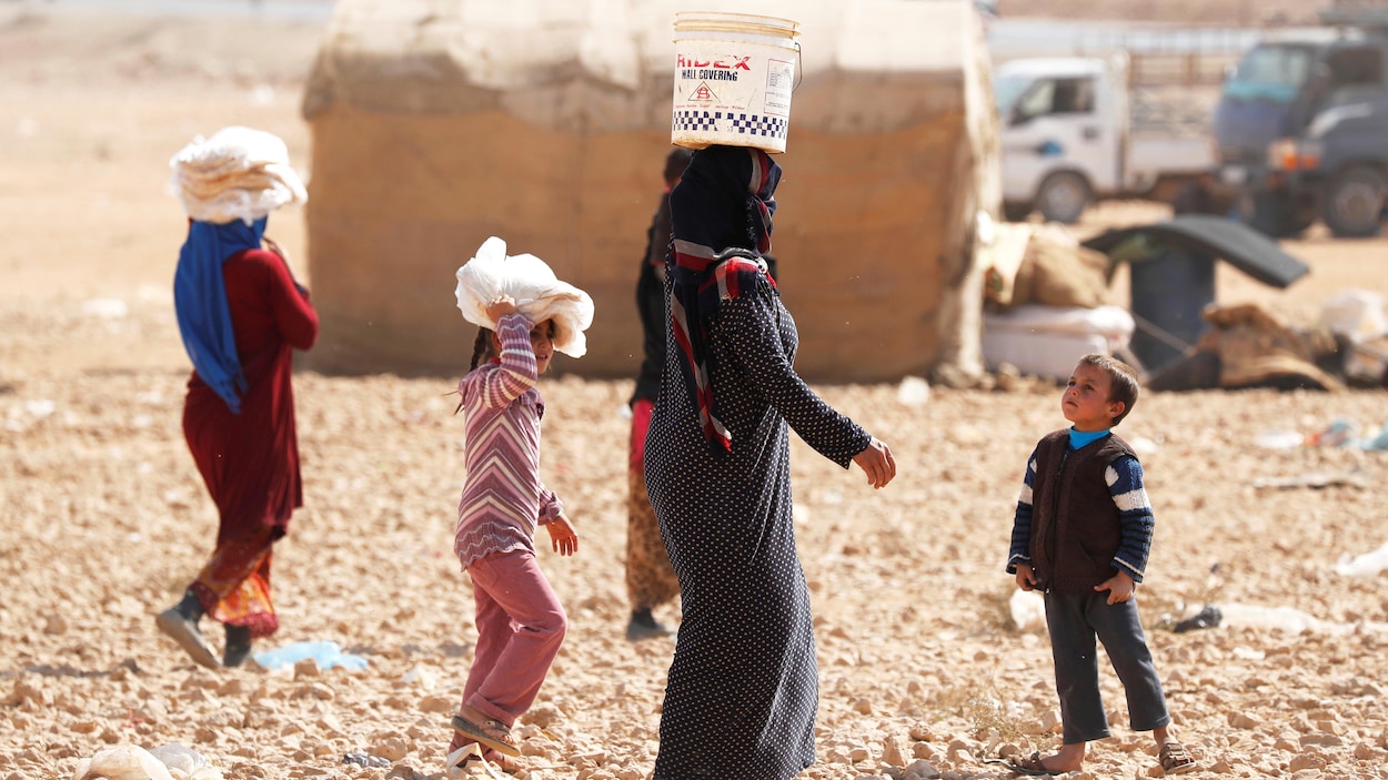Une femme transportant de l'eau dans un camp de réfugié en Syrie.