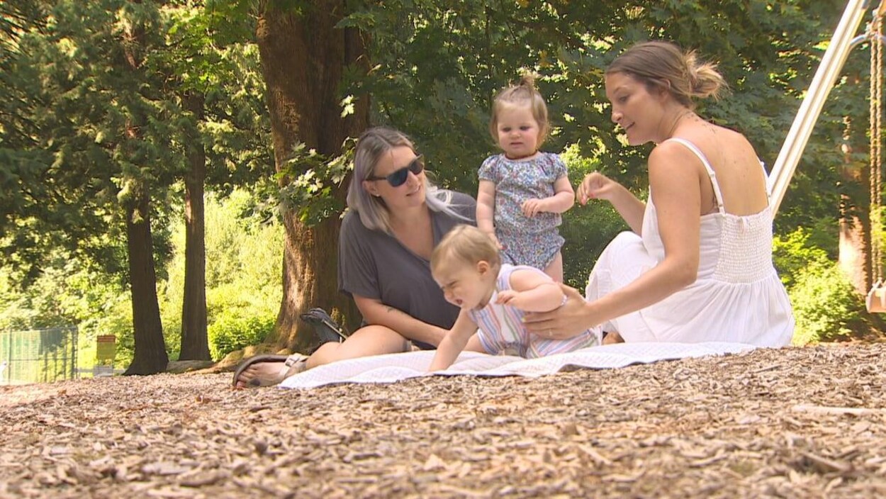 Deux mères jouent dans un parc avec leurs enfants.