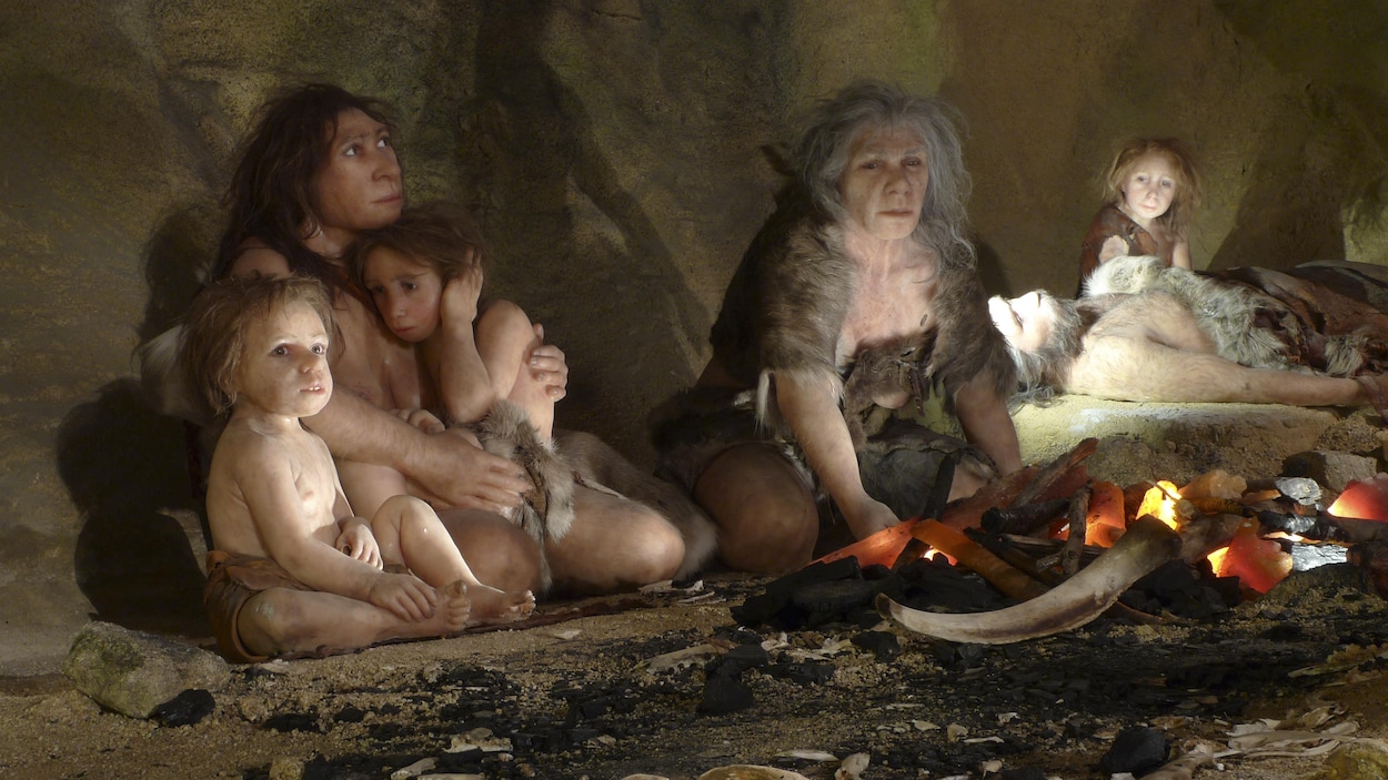 Reconstitution d'une scène de vie de Néandertal dans une caverne. On voit des femmes et des enfants assis autour d'un feu.