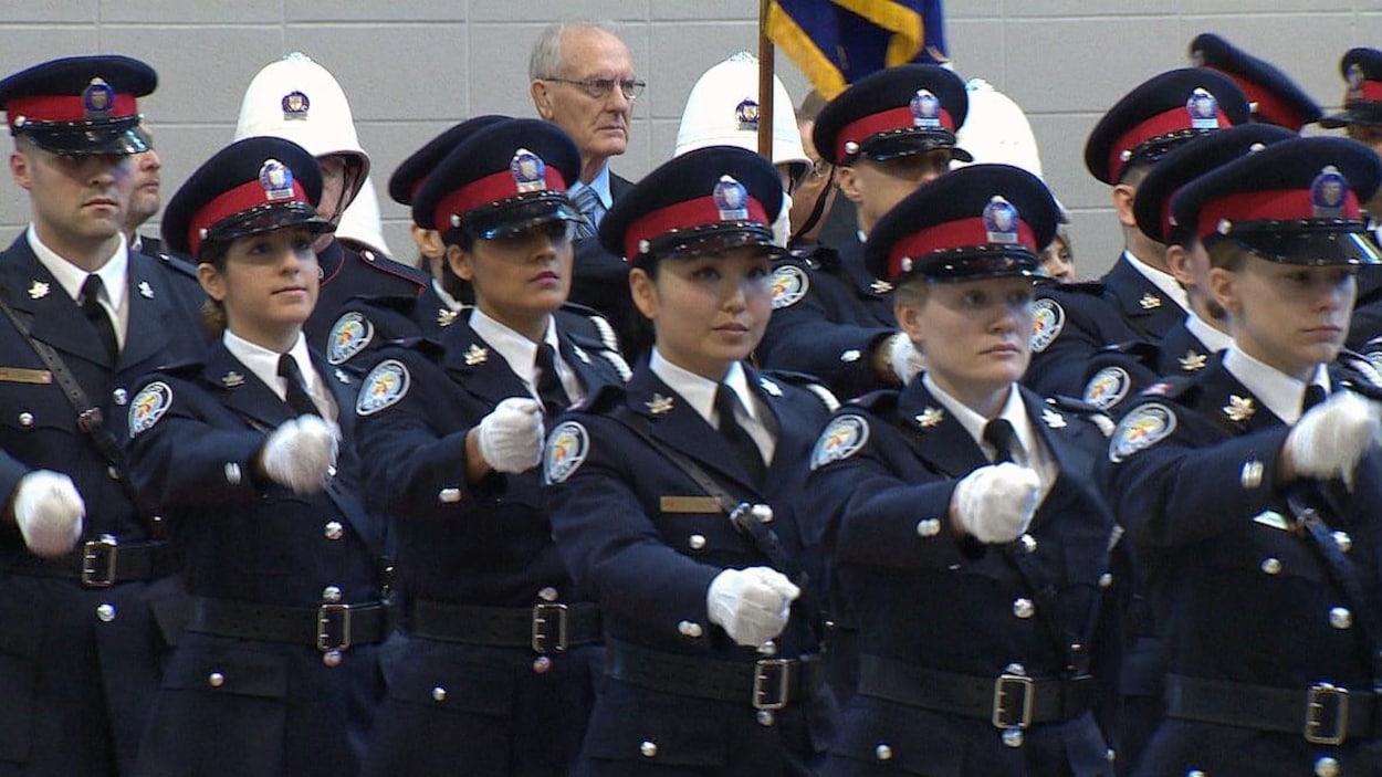 Des femmes et des hommes en uniforme de la police de Toronto, en rang, lors d'une cérémonie.
