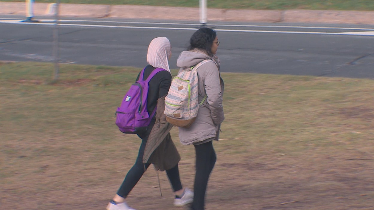 Deux étudiantes, dont une portant un hijab, marchent sur un campus Deux étudiantes, dont une portant un hijab, marchent sur un campus
