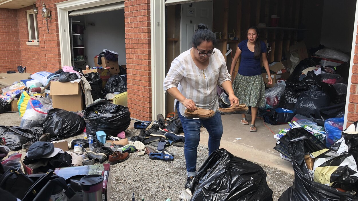 Deux femmes trient des objets ramassés dans deux garages remplis de sac de dons.