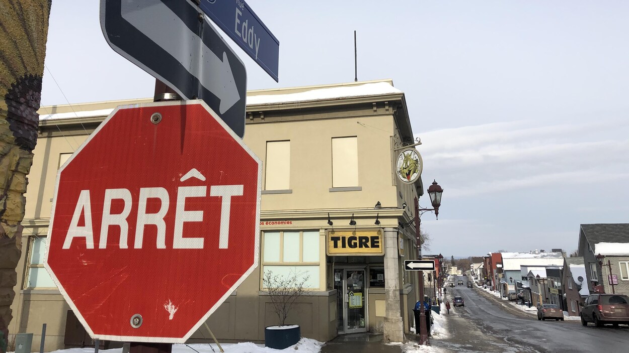 Un panneau d'arrêt avec, au-dessus, les noms des rues Frontenac et Eddy. Derrière, la façade du Tigre Géant et la rue Eddy en perspective.