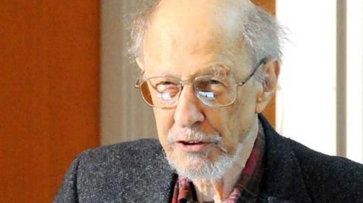 Fernando Corbato, un homme au crâne dégarni et portant des lunettes, un veston gris et une chemise à carreaux rouge.