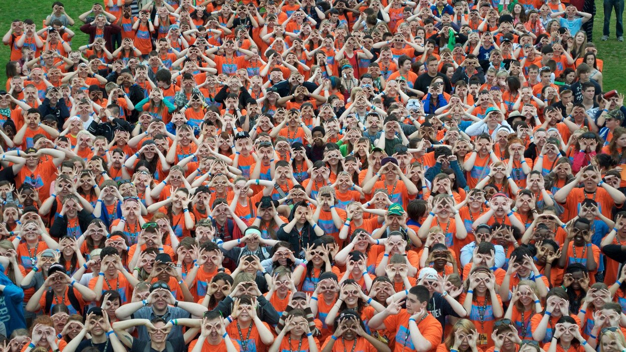 Une foule de jeunes gens qui miment des lunettes avec leurs doigts. Une foule de jeunes gens qui miment des lunettes avec leurs doigts.