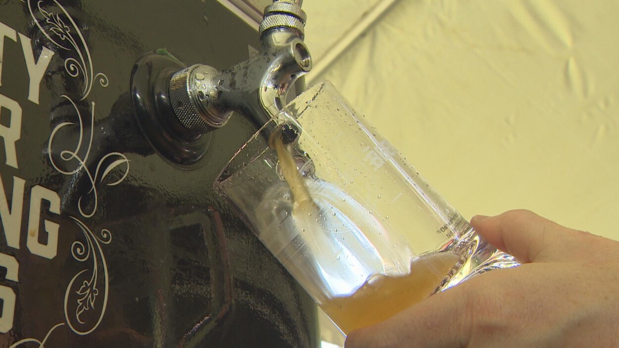 une main tient un verre qui est en train d'être rempli de bière