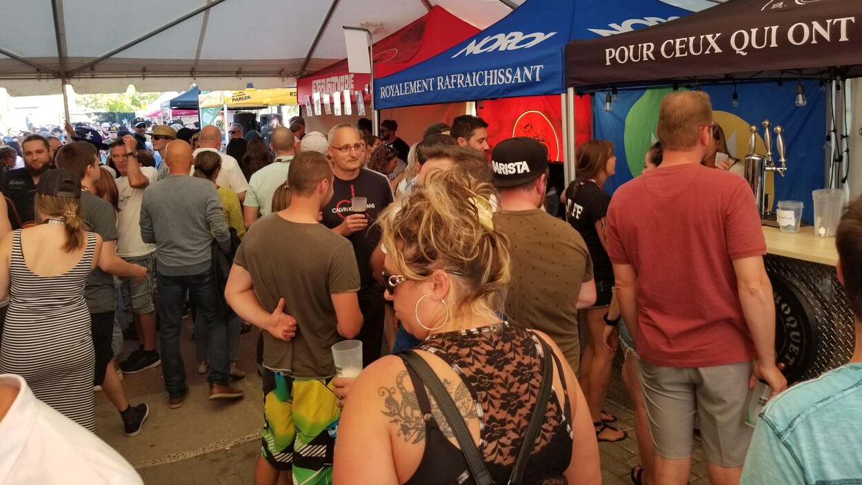 Des gens sous un chapiteau boivent de la bière.