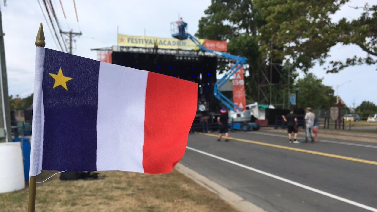 Un drapeau acadien devant une scène extérieure.