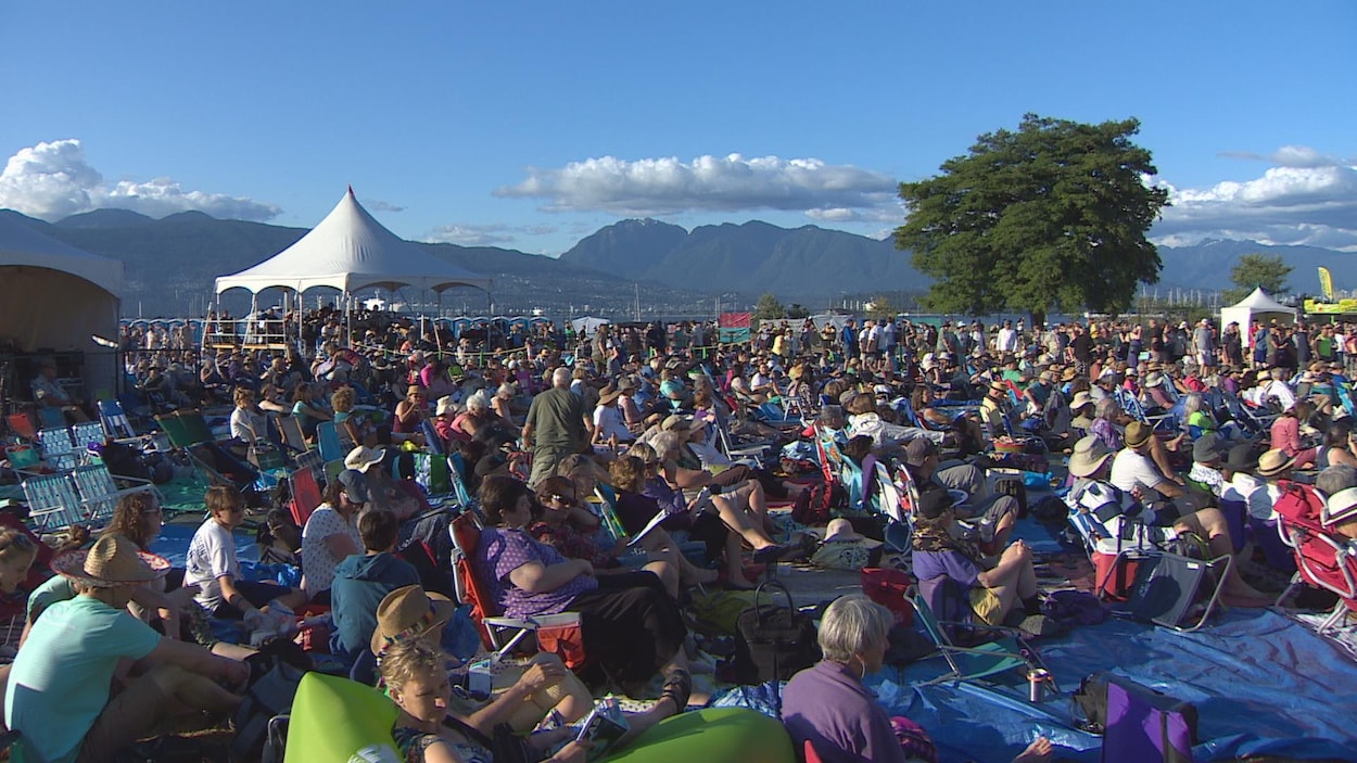 Les spectateurs de festival de folk de Vancouver assistent aux concerts avec les montagnes dans l'arrière-plan Les spectateurs de festival de folk de Vancouver assistent aux concerts avec les montagnes dans l'arrière-plan