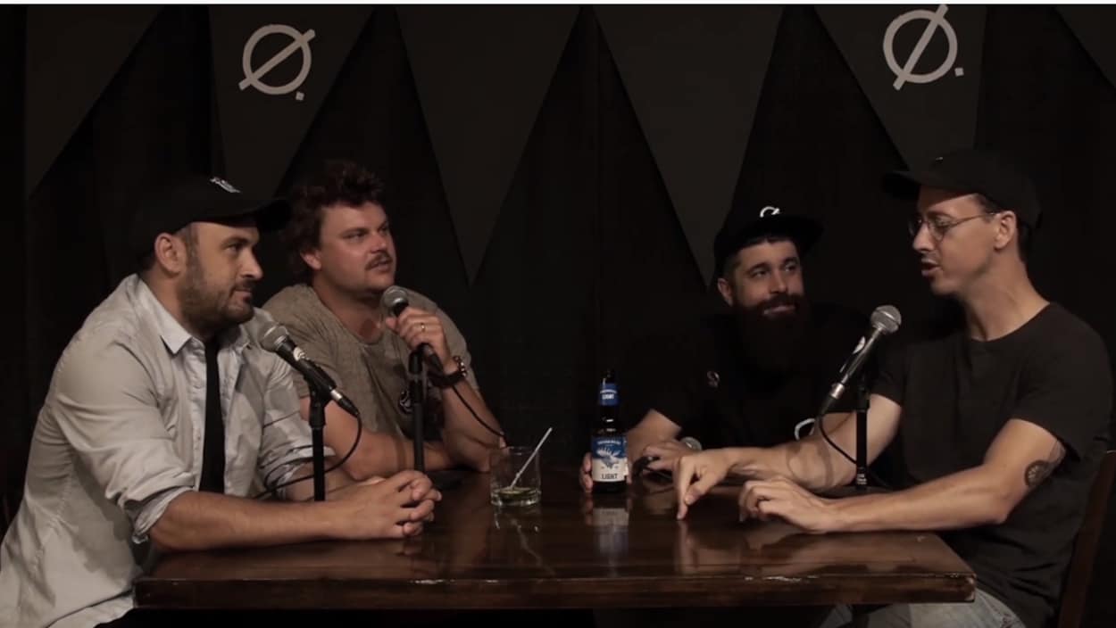 4 humoristes discutant autour d'une table avec des micros.
