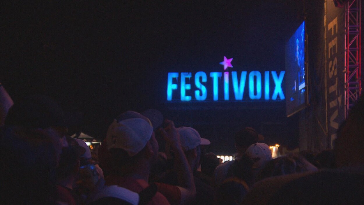 Gens qui regardent une scène avec les lettres du Festivoix en gros