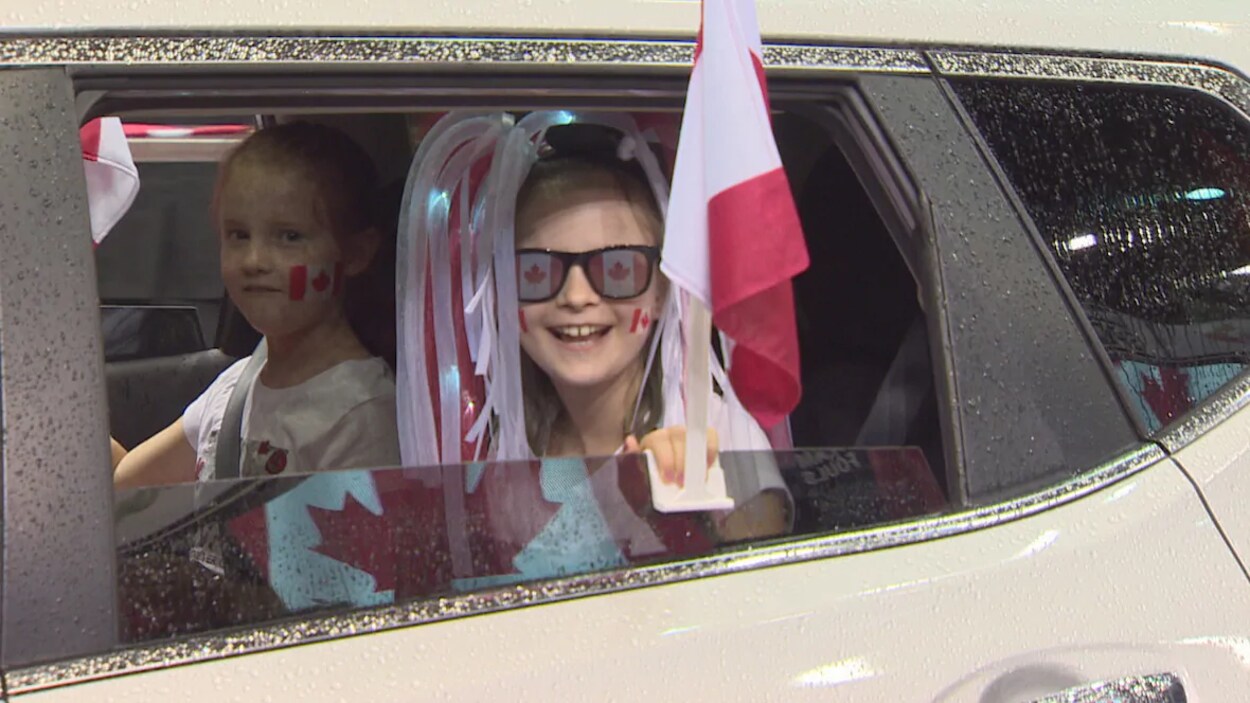 Deux petites filles assises dans une voiture se sont décorées du drapeau canadien lors de la fête du Canada, le 1er juillet 2020