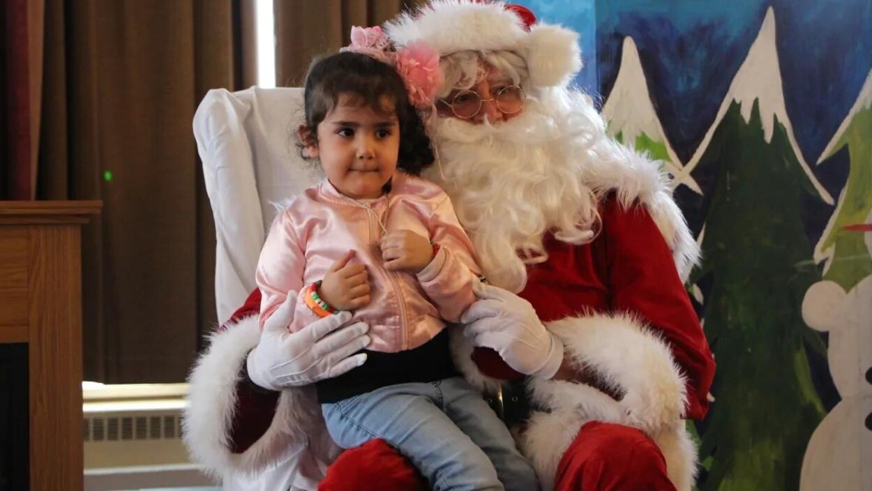 Une enfant assis sur les genoux d'un père Noël.