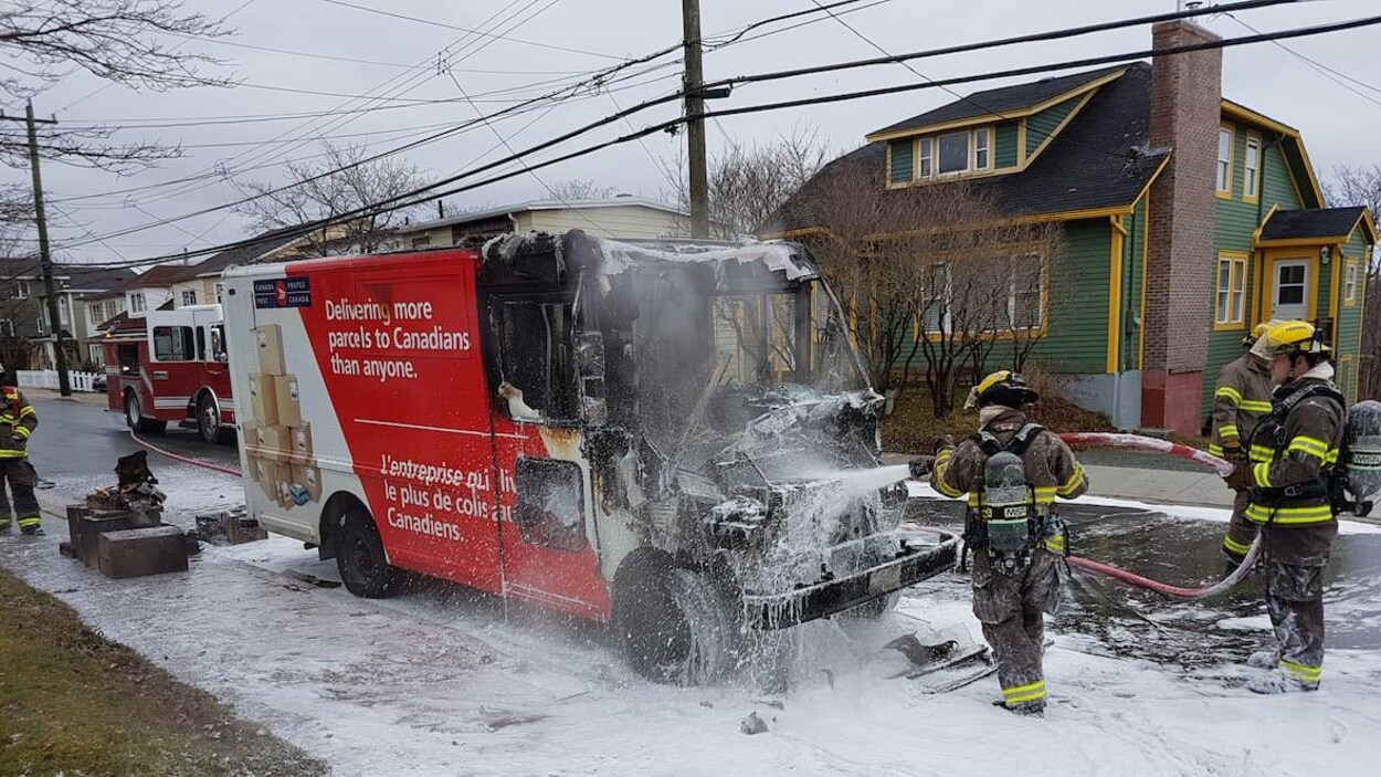 Des pompiers arrosent un camion de Postes Canada.