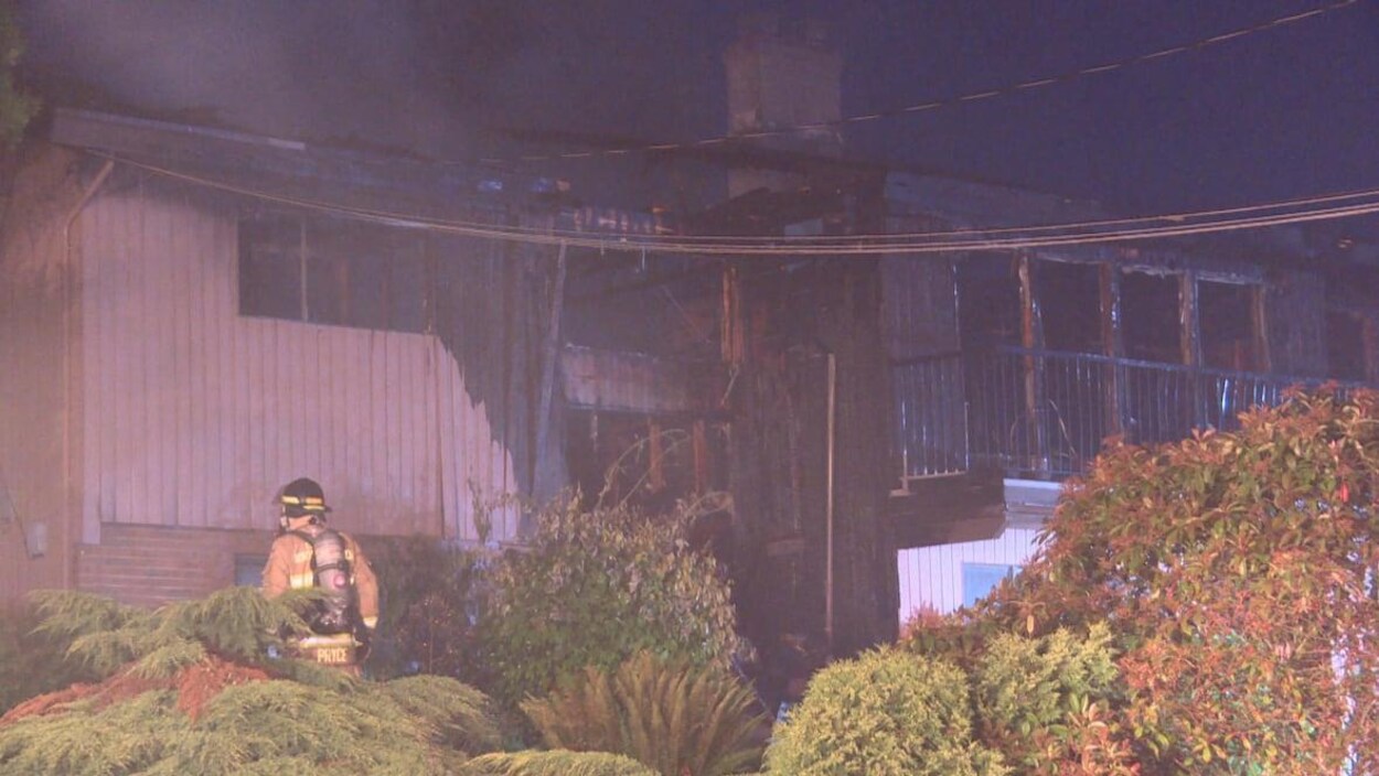Un pompier devant une maison ravagée par un incendie.