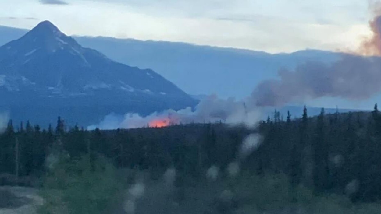 Des flammes visible de loin au pied d'une montagne