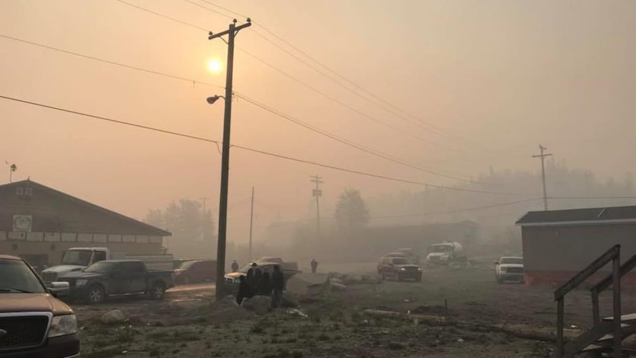 Un ciel orange de fumée avec devant, une petite communauté.